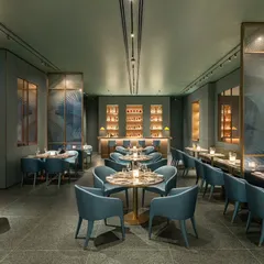 This comprehensive view of the Armani Caffe interior captures the full length of the restaurant. It shows the flow from the dining tables in the foreground to the bar in the back, emphasizing the spaciousness and cohesive design of this luxury establishment.
