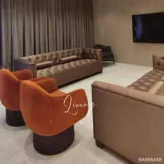Comfort is key in a living space. We selected plush, comfortable seating, including deep-cushioned tufted sofas and vibrant orange swivel armchairs, to create a luxurious and functional entertainment room.