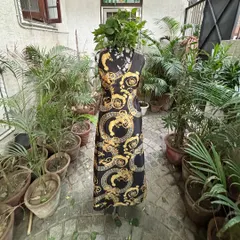This black and gold print maxi dress, seen here on a mannequin, is all about the cut and fit. It’s a made-to-order piece that we tailor to your exact measurements for a flawless look.