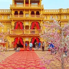 A palace-front wedding venue transformed with cherry blossom trees and a grand patterned red carpet, showing how I handle large-scale, opulent wedding decorations.