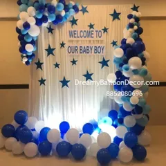 A beautiful backdrop I created to welcome a baby boy. It features a white curtain with blue stars, a "Welcome to our Baby Boy" sign, and is framed by an organic balloon garland in shades of blue and white.