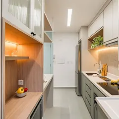 A galley kitchen designed for maximum efficiency in a compact space. The light green and wood-tone cabinets, along with open shelving and under-cabinet lighting, make the area feel bright and functional.