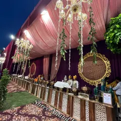 A lavish buffet spread with ornate chafing dishes, set against a backdrop of purple velvet and illuminated by hanging chandeliers.