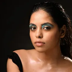 A direct, powerful gaze in this shot emphasizes the unconventional eyeshadow placement and dewy skin finish.