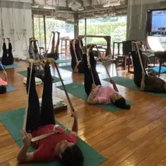 A class in session, with students using belts for Supta Padangusthasana. This shows the collective energy of a group practice, where everyone is on their own journey but supported by the community.