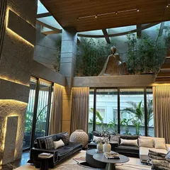 This double-height living room is a perfect example of monochrome elegance and sustainability. The large windows flood the space with natural light, while the concrete and stone elements connect the interior to the earth.