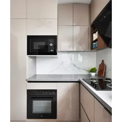 This compact kitchen is designed for maximum efficiency. It features glossy beige acrylic cabinets, a built-in oven and microwave tower, and a durable grey quartz countertop that extends up into a seamless backsplash.