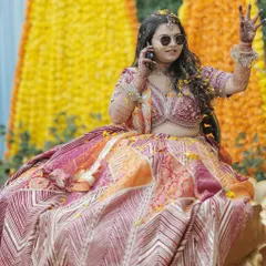 A cool bride on the phone during her Haldi. Her makeup is effortless and chic, with a subtle glow that enhances her features.