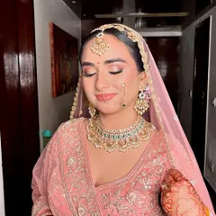 Radiating a beautiful bridal glow in her pastel pink lehenga. This look is all about grace and sparkle, with soft pink eyeshadow, rosy cheeks, and a gentle smile.