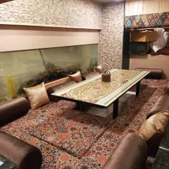 My Dastarkhwan seating area next to a large aquarium, offering a unique and relaxing dining environment. It's a perfect spot for a memorable family dinner.