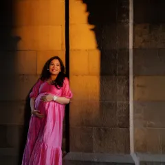 The magic of golden hour light meeting the joy of motherhood. I love how the architectural shadows create a natural frame, highlighting her smile and the miracle she holds. This is a perfect example of a fine art maternity portrait.