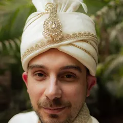 A close-up portrait of the groom, focusing on the intricate details of his wedding turban (safa). His calm expression reflects the significance of the day.