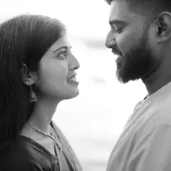 A classic black and white close-up, focusing on the couple's profiles as they share a look. The monochrome treatment emphasizes their expressions and the emotional connection between them.