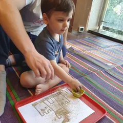 This young boy is focused on his sand castle art, using a small scoop to add sand. It’s a calm and engaging sensory activity.