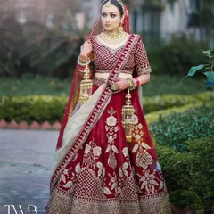 A full-length portrait showcasing the bride's magnificent wedding lehenga. Standing gracefully in a garden, she holds her kalire, embodying the timeless elegance of an Indian bride.