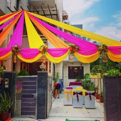 A similar house decoration for a pre-wedding function, showing the bright fabric canopy and simple chair setup in the driveway for arriving guests.