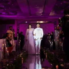 The couple's grand entrance down a mirrored aisle, reflecting the purple-lit glamour of their reception hall.