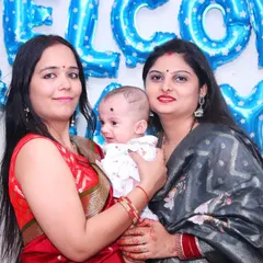 Family members holding a newborn baby in front of a 'Welcome Baby Boy' balloon decoration.