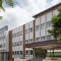 A daytime view of the Jindal Public School, where our facade design aimed for a timeless and simple aesthetic. The building's clean lines and textured grey finish are designed to withstand the highway environment while inspiring the students within.