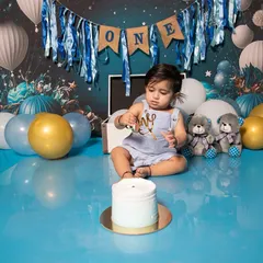 A simple cake, a beautiful space-themed backdrop, and one curious little boy. This is the moment just before the smashing begins, full of anticipation for his first birthday celebration.