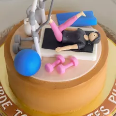 A close-up of the "Bride to be Pilates Pilla" cake, showing the detailed fondant work on the figure and equipment.
