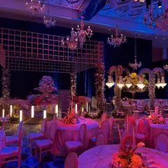 A view of the reception layout, where elegant chandeliers and floral arches create intimate zones within a grand space. The mood lighting adds a touch of drama and sophistication. ✨🌸