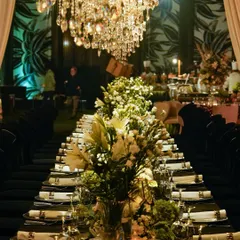 A dramatic view of the long banquet table, with black linens and chairs creating a powerful contrast against the white florals and sparkling chandeliers.