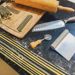 The tools of the trade for pasta making. A rolling pin, pasta wheel, and fresh dough are all that's needed to begin the process of creating something special.