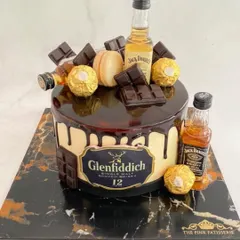 A Glenfiddich and Jack Daniel's themed drip cake, loaded with Ferrero Rocher, chocolate bars, and miniature liquor bottles.