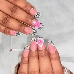 A fun twist on a classic print. This look combines a zebra print French tip on square nails with a soft pink base and a delicate, 3D pink flower for a pop of color.
