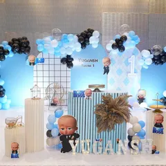 This Boss Baby theme uses a cool palette of black and blue. The backdrop features a modern grid pattern, character cutouts, and themed props like a miniature bicycle and birdcage for a stylish look.