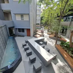 This outdoor common area at the university includes a long, modern water feature and contemporary stone seating cubes. The space is designed to be a cool and refreshing spot for students to gather and collaborate.