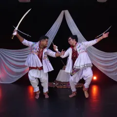 The energy between two performers is key in a duet like this. Here, we are captured mid-movement during a dynamic sword dance sequence, showcasing the precision and power involved.