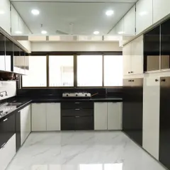 A full view of the black and white kitchen, showing the efficient layout and abundant storage, including overhead cabinets that reach the ceiling. The glossy finish on the cabinets reflects light, making the space feel bright and open.