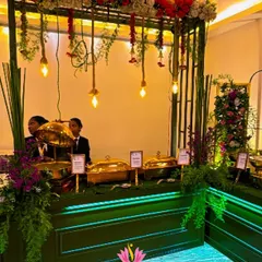 A closer look at the serving area of the Green and Gold buffet. The warm lighting from the hanging bulbs highlights the golden chafing dishes, making the food look even more appetizing.