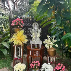 A sacred corner for blessings, featuring a silver Ganesha idol, traditional flower arrangements, and carved wooden screens.