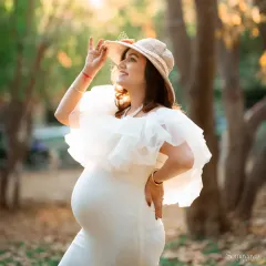 A portrait of a glowing mother-to-be, enjoying the sunshine. The hat adds a touch of elegance to this outdoor maternity session, highlighting her joyful anticipation.