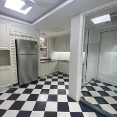 A timeless black-and-white checkered floor gives this kitchen a classic yet bold character. We paired it with off-white custom cabinetry and a stainless steel refrigerator for a look that is both vintage-inspired and modern.