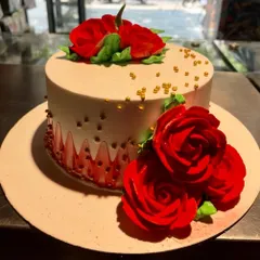 A simple yet stunning cake adorned with vibrant, handcrafted red sugar roses. The sprinkle of gold beads adds a touch of elegance to this classic design.