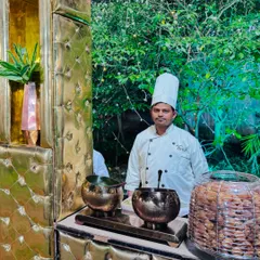 My chef stands ready at the chaat station, which is elegantly decorated with golden bowls and lush greenery.