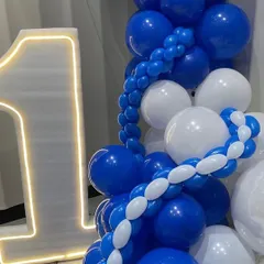 A close-up of the decor for the corporate anniversary, showing the "1" LED number next to a cascade of blue and white balloons, with a Ganesha idol for blessings on the milestone.