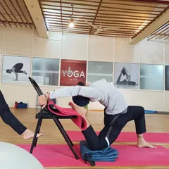 A student practices a supported backbend using a chair. This demonstrates how props can be used to work towards more advanced poses like Kapotasana (Pigeon Pose) safely and effectively.