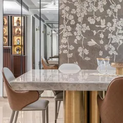The dining area features a magnificent marble tabletop with a sculptural brass base. A custom stone mosaic wall provides an artistic backdrop, while mirrored panels expand the sense of space and reflect the room's opulent details.