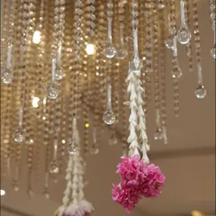 A detail shot of a crystal chandelier with hanging strings of fresh flowers. This shows how I blend modern decorative elements with traditional touches to create a unique and elegant look for religious events.