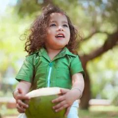 A candid outdoor portrait of a little boy enjoying a fresh coconut. We love capturing these simple, authentic moments of childhood.