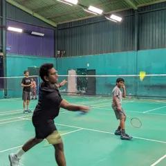 A coach demonstrates the proper form for a shot while a junior player observes. Our sessions involve a mix of active drills and direct instruction.