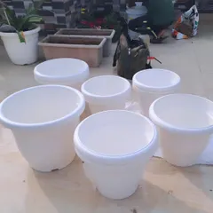 Getting ready for a planting project. A collection of clean, white plastic pots of various sizes are prepared before being filled with soil and new plants.