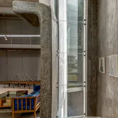 A detail of the cast-in-situ concrete and glass elevator shaft within the Artrovert studio, showcasing the project's honest and expressive use of materials.