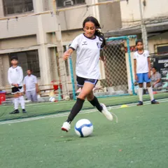 With perfect form, a player from our girls' team strikes the ball, demonstrating the powerful shooting technique she has developed through our coaching.