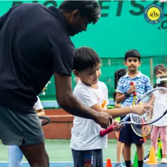 A coach adjusts a young boy's grip on the racquet. I believe in nurturing young talent by focusing on the fundamentals one swing at a time.